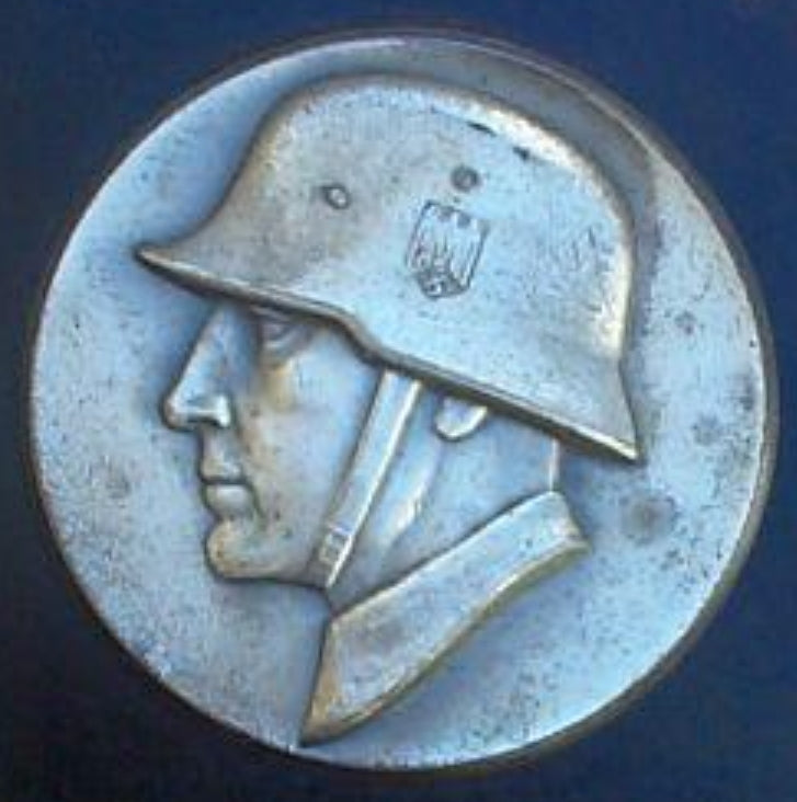 Deutsches versilbertes Metallschild aus dem Zweiten Weltkrieg mit Darstellung eines Wehrmachtssoldaten.